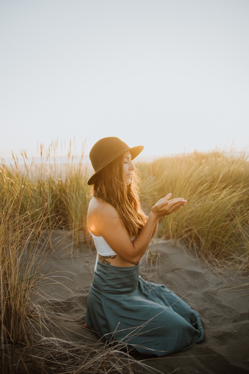 Aligned online spiritual coach sitting on beach with hands open