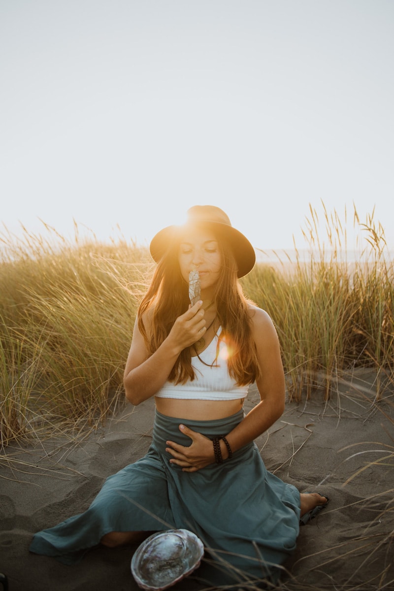 arise alchemy embodied women on beach with sage holding belly