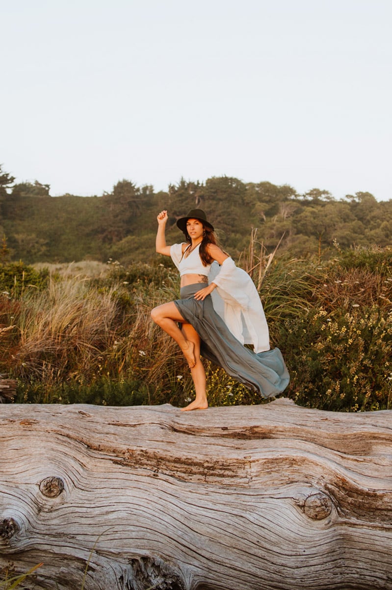 female empowerment coaching lauryn on log with one arm up