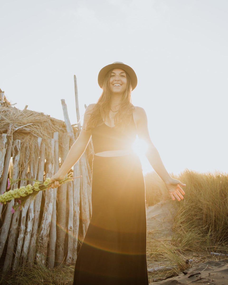 somatic coaching and embodiment mentor standing on the beach with arms open